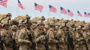 Soldiers in formation with American flags behind.