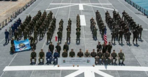 Military personnel gathered on aircraft carrier deck.