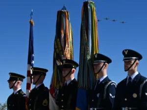 Military honor guard with jets flying overhead.